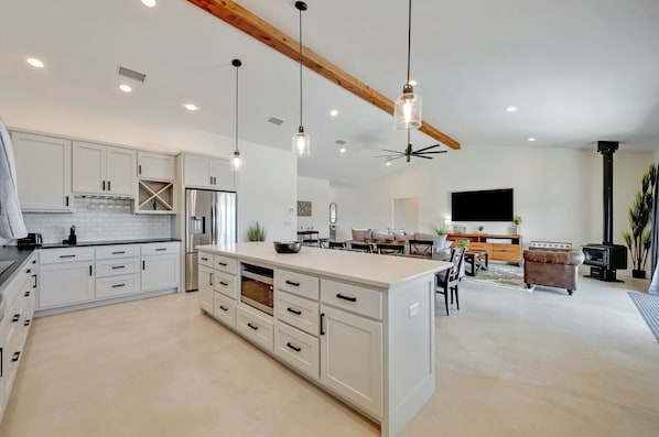 A spacious kitchen with white cabinetry, a central island, and pendant lighting. - Secluded Hill Country Getaway • Stunning Views + Fire Pit • 15 Min to Main St (Fredericksburg)