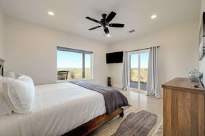 A bedroom with a bed, a ceiling fan, a TV, and a view of the outdoors. - Secluded Hill Country Getaway • Stunning Views + Fire Pit • 15 Min to Main St (Fredericksburg)
