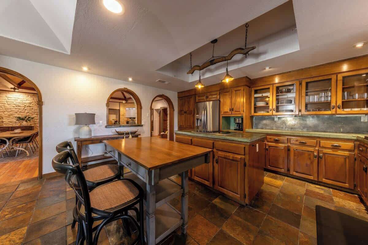 Un'ampia cucina con mobili in legno, un'isola centrale e un'area pranzo con sedie.