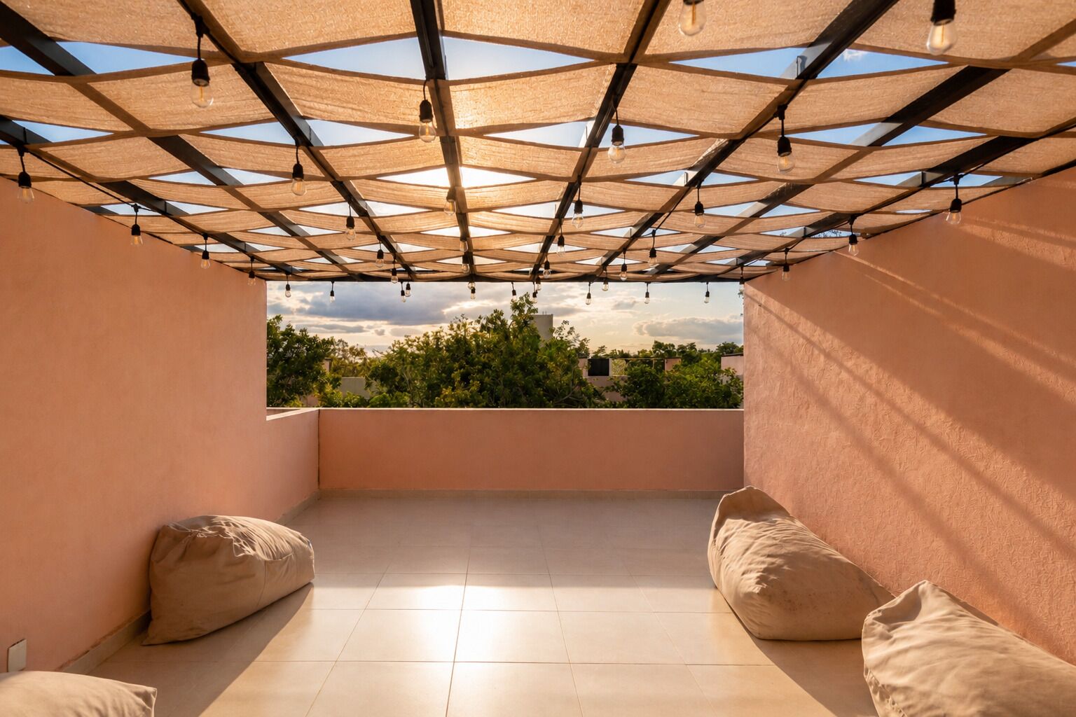 Une terrasse sur le toit offrant une vue sur la verdure, une pergola agrémentée de guirlandes lumineuses et deux fauteuils en forme de sac de haricots.