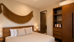 Una habitación de hotel con cama, mesitas de noche, armario y puerta.