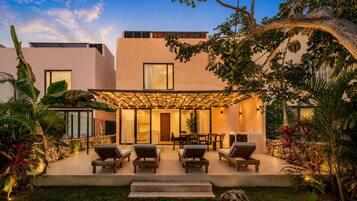 Uma casa moderna com um pátio, área de estar externa e vegetação exuberante.