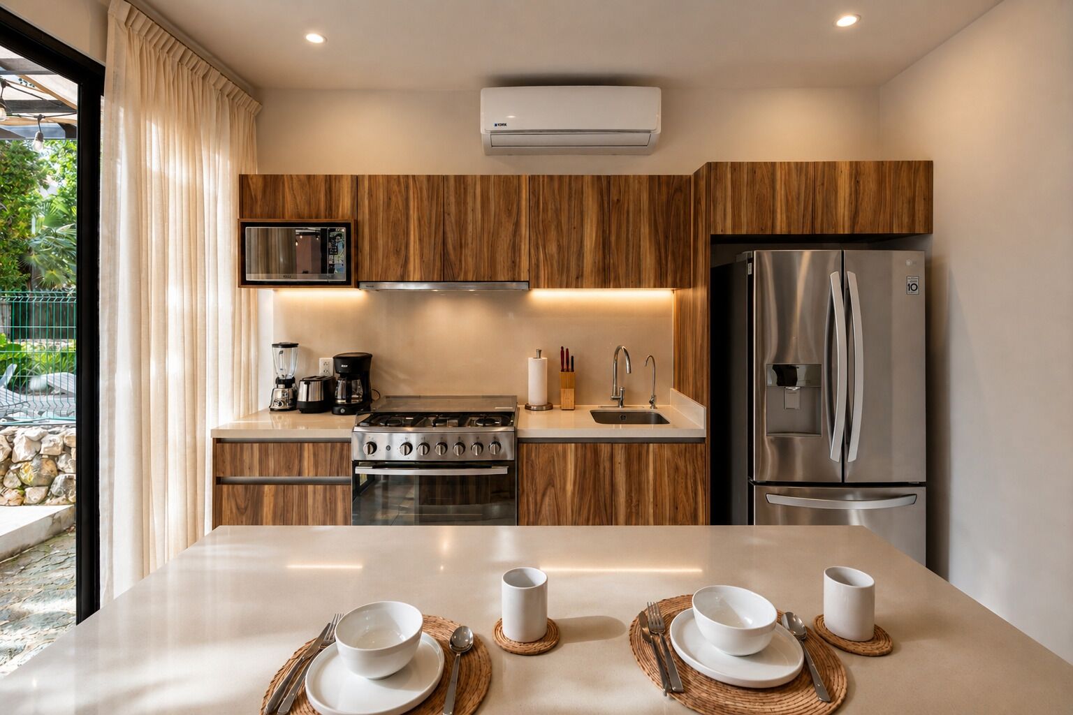 A modern kitchen with wooden cabinets, stainless steel appliances, and a dining area set for four.