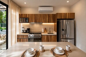 A modern kitchen with wooden cabinets, stainless steel appliances, and a dining area set for four.
