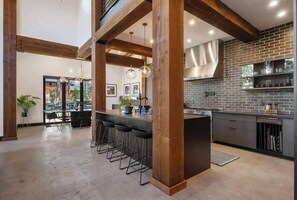 Een moderne keuken met open bakstenen muren, houten balken en een bar met krukken.