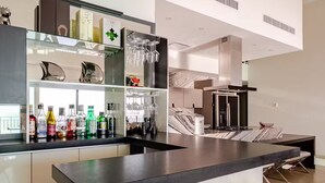 Une cuisine moderne avec un coin bar, des meubles blancs et un pare-feu en marbre.