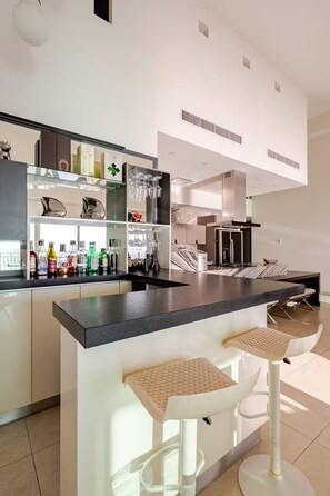 A modern kitchen with a bar area, white cabinetry, and a marble backsplash. - Beautiful beachfront penthouse with private pool (Puerto Vallarta)