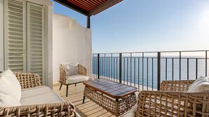 Un balcon agrémenté de meubles en osier, d’une table et offrant une vue sur la mer.
