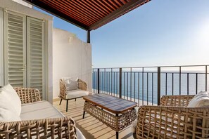 A balcony with wicker furniture, a table, and a view of the sea. - Beautiful beachfront penthouse with private pool (Puerto Vallarta)