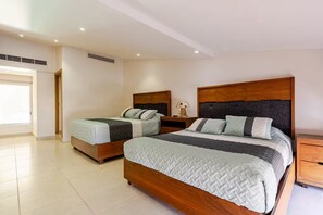 Quarto com duas camas, mesa de cabeceira, luminária e janela.