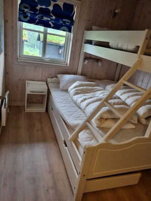 A bunk bed room with a window, a small bedside table, and a wooden floor. - Vrbo Property (Myrkdalen)