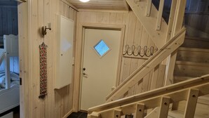 A wooden interior with a staircase, a door with a window, and a wall-mounted light fixture. - Myrkdalen stay (Myrkdalen)