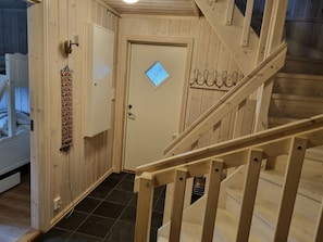 A wooden interior with a staircase, a door with a window, and a wall-mounted light fixture. - Myrkdalen stay (Myrkdalen)