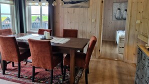 A dining area with a wooden table, red chairs, a patterned rug, and a view of a house through the window. - Myrkdalen stay (Myrkdalen)