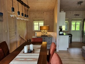 A wooden interior with a dining table, chairs, a lamp, and a kitchen area. - Vrbo Property (Myrkdalen)