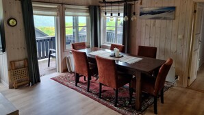 A wooden interior with a dining table, chairs, a rug, and a view through the glass door. - Myrkdalen stay (Myrkdalen)