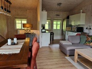 L’intérieur d’un chalet en bois comprend un coin repas, un canapé et une petite cuisine.