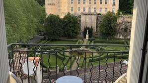 Varanda com mesa e cadeiras, dando vista para um pátio com um edifício ao fundo.