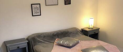 Une chambre à coucher avec un lit, une table de chevet, une lampe et des œuvres d’art murales.
