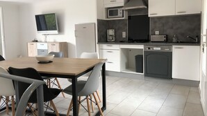 Uma cozinha moderna com armários brancos, micro-ondas, cafeteira e lava-louças.
