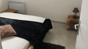 Quarto com cama, mesa de cabeceira, luminária, espelho e janela.