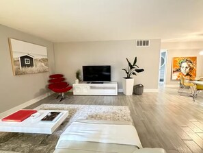 A modern living room with a flat-screen TV, red chairs, a white sofa, and a dining area with yellow chairs. - Gorgeous1BED Beach Walk distance in Fort Lauderdale (Fort Lauderdale)