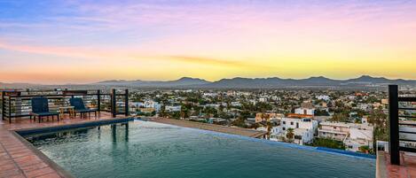 A rooftop pool with a view of a cityscape and mountains.