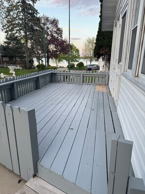 A wooden deck with a white picket fence, a street lamp, and a house in the background.