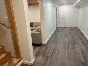 Ein Flur mit einer Holztreppe, einem grauen Sofa und einer Tür.