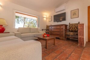 Ein Wohnzimmer mit Sofa, Couchtisch, Fernseher und einem gemusterten Sessel.