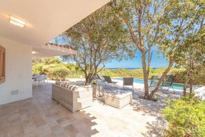 Eine Außenpatio mit Sitzgelegenheiten, einem Pool und Blick auf das Meer.