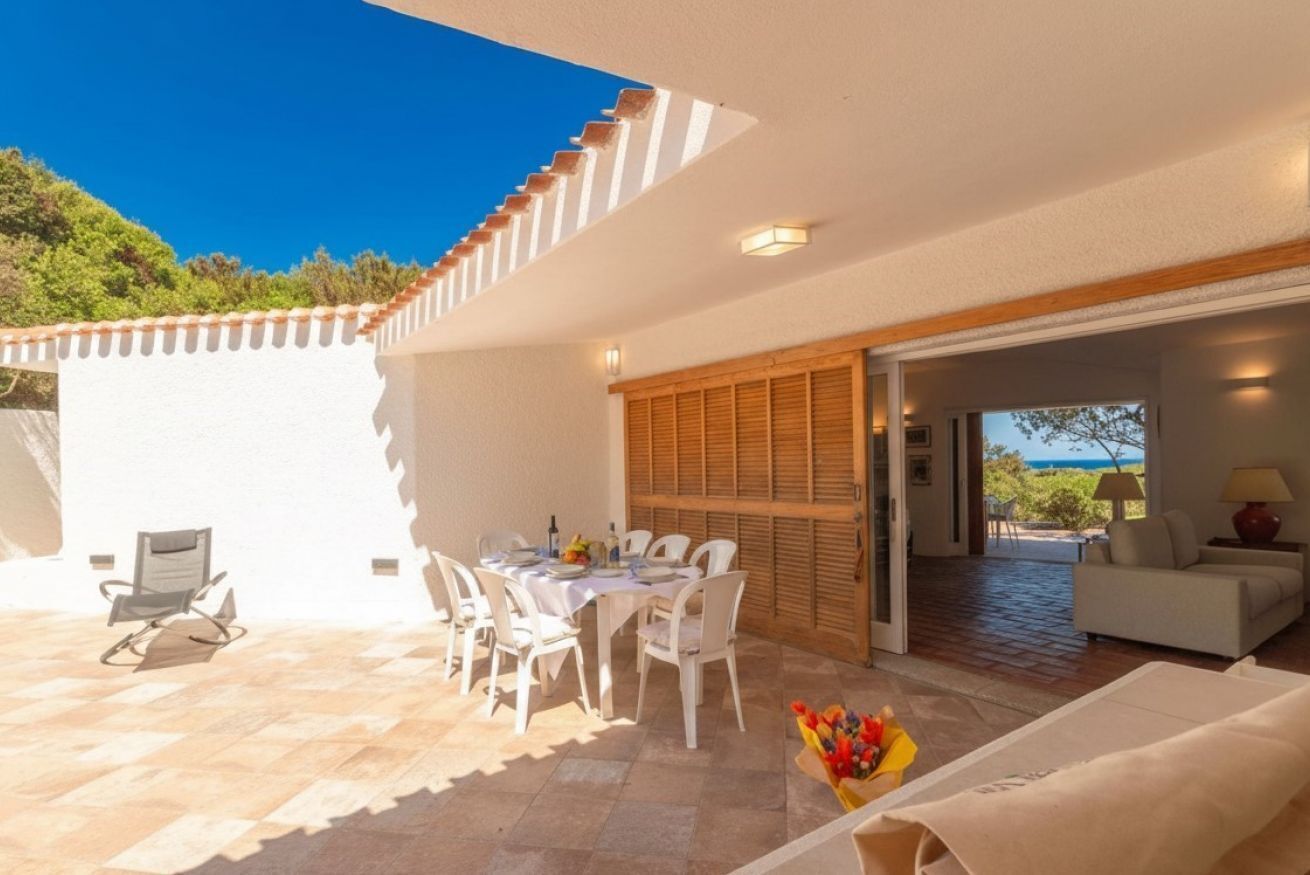 Un patio exterior con mesa y sillas, un sofá y vista al mar.