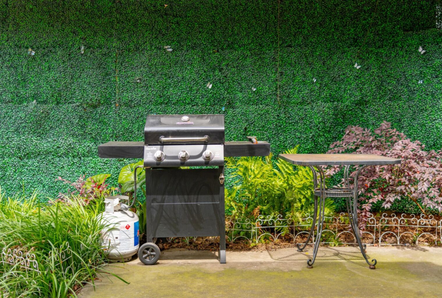 A barbecue grill with a table and a decorative fence in a garden setting.