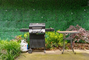 A barbecue grill with a table and a decorative fence in a garden setting. - Heart of Folly Beach: Walk Everywhere, Sleeps 5 (Folly Beach)
