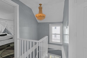 A room with a staircase, a chandelier, and a bed. - Perfect 4-bedroom house with EV Charger in pleasant Buffalo neighborhood (Buffalo)