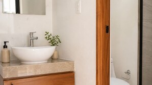 Une salle de bain avec un lavabo blanc, un miroir, un meuble en bois et des toilettes.