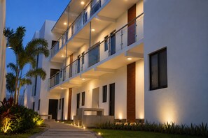A multi-story hotel with balconies, a covered walkway, and a well-lit entrance.