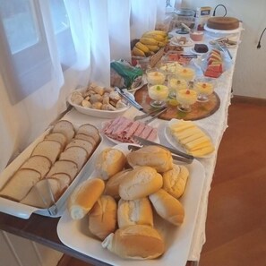 A buffet table with various food items including bread, pastries, and fruits. - Recanto Due Fratelli (Campos do Jordão)