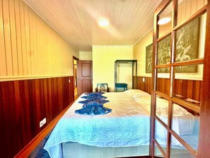 Ett hotellrum med en säng, träpanel på väggarna, en glasdörr och konstverk på väggen.