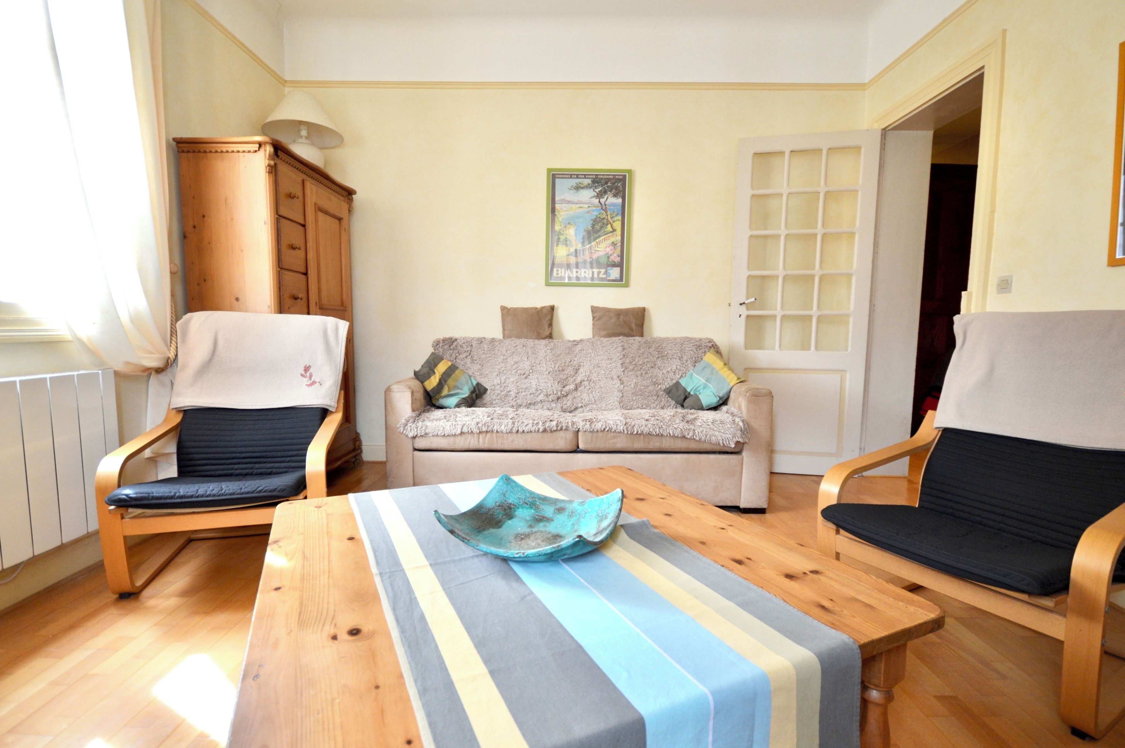 A living room with a sofa, two armchairs, a wooden coffee table, and a cabinet.