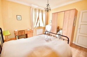A bedroom with a bed, a desk, a chair, a wardrobe, and a radiator. - Vrbo Property (Biarritz)