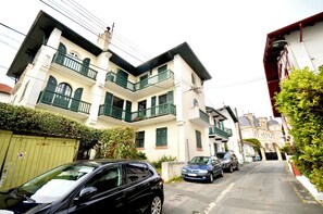 A multi-story residential building with balconies, parked cars, and a gated entrance. - Vrbo Property (Biarritz)