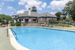 A swimming pool with a metal handrail, lounge chairs, and a stone building with a tower in the background. - Las Colinas Retreat Near Toyota Music Factory, DFW & Convention Ctr (Irving)