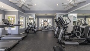Une salle de sport équipée de tapis de course, de vélos elliptiques et de poids libres.