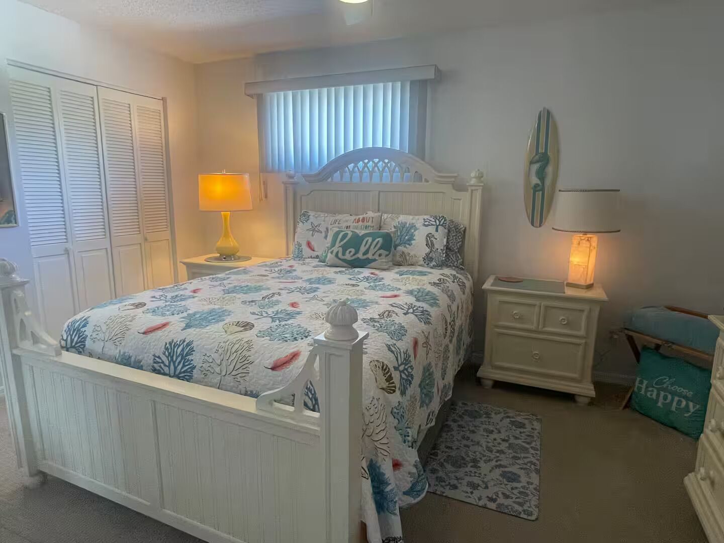 A bedroom with a bed, nightstands, a window with blinds, a radiator, and a small rug.