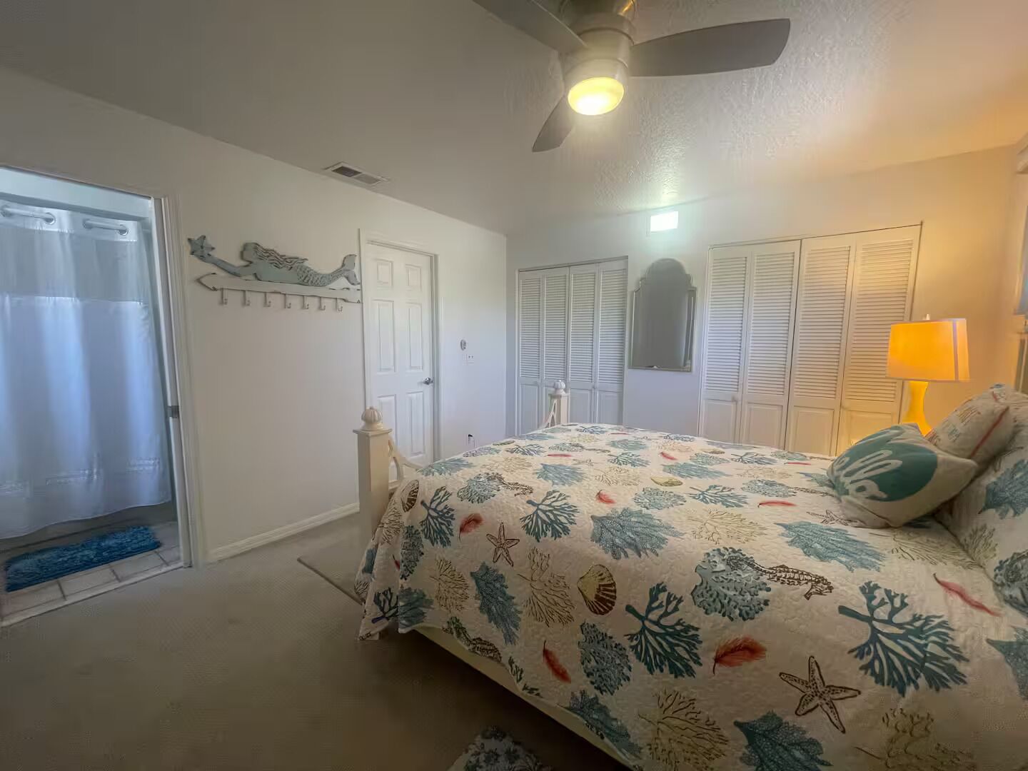 Ein Schlafzimmer mit Bett, Deckenventilator, Tür und Fenster.