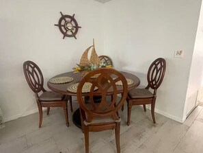 Un tavolo da pranzo con quattro sedie, una decorativa ruota di nave a parete e un centrotavola intrecciato.