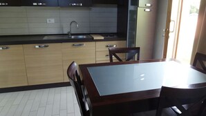 A kitchen with wooden cabinets, a black countertop, a sink, and a dining table with chairs. - Relax nel Verde 1 - One Bedroom Apartment, Sleeps 2 (Calafuria)