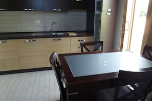 A kitchen with wooden cabinets, a black countertop, a sink, and a dining table with chairs. - Relax nel Verde 1 - One Bedroom Apartment, Sleeps 2 (Calafuria)