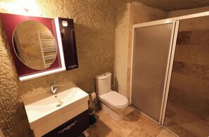 A bathroom with a sink, toilet, and a shower area. - Pasha cave  (Nevşehir)